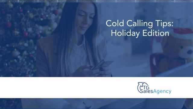 A professional woman checking her phone in a holiday office setting, representing intentional cold calling and sales outreach during the holidays.