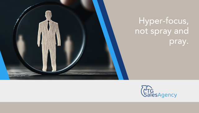 Magnifying glass focusing on a wooden business figure symbolizing precision targeting in B2B sales with the words ‘Hyper-focus, not spray and pray’ and TG Sales Agency logo.
